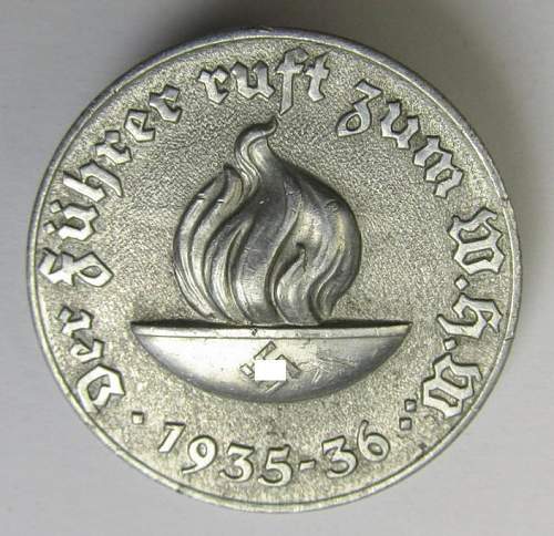 Aluminium W.H.W. ('Winterhilfswerke'-) related badge &quot;Der Führer ruft zum W.H.W. - 1935-36&quot; with flame image.